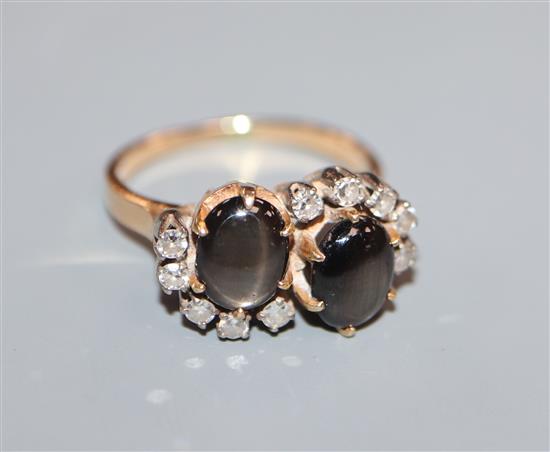 A yellow metal, twin stone cabochon cats eye cabochon and diamond set crossover ring, size M.